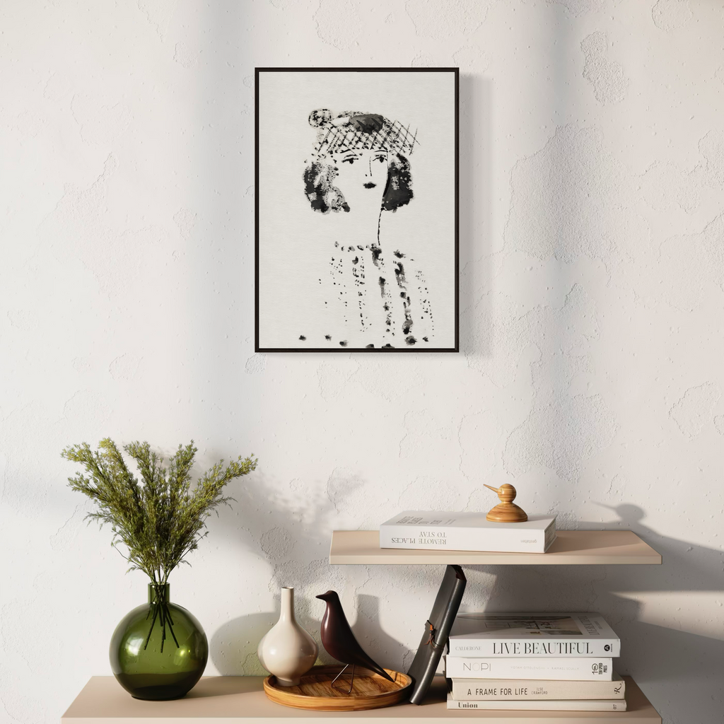 Framed black and white portrait of a young woman art print on a wall above a shelf with decorative items.
